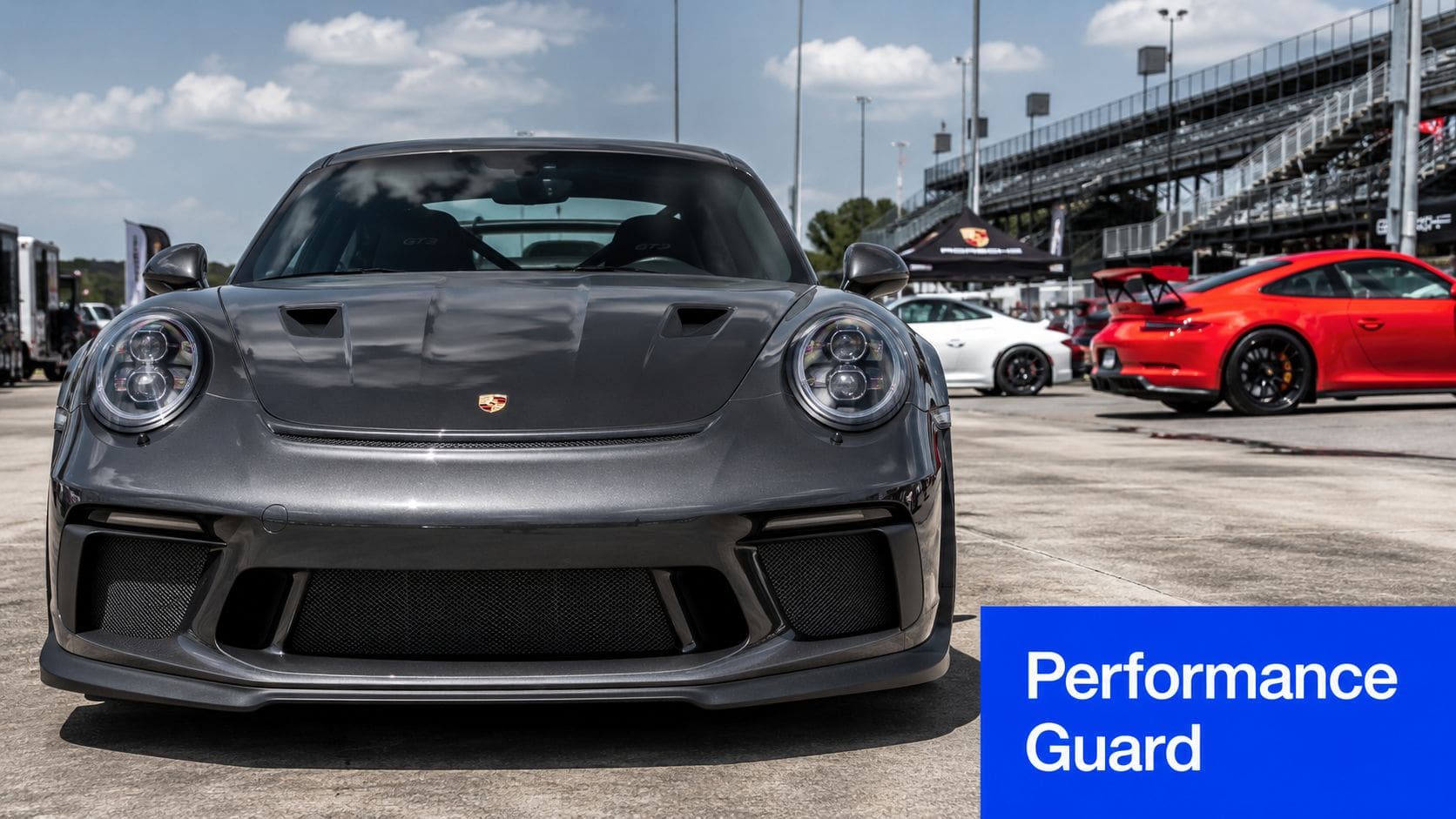 A sleek dark grey Porsche GT3 parked on a track, featuring a full front PPF protective wrap.